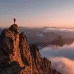 Failure Isn’t Final: A resilient figure standing on a mountain peak at sunrise, symbolizing strength after setbacks.