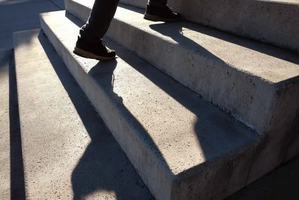 Person climbing concrete steps at sunrise, symbolizing the 1% Rule of small daily wins creating big results.