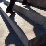 Person climbing concrete steps at sunrise, symbolizing the 1% Rule of small daily wins creating big results.