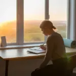 A person practicing morning routine discipline by planning their day at sunrise to boost productivity.